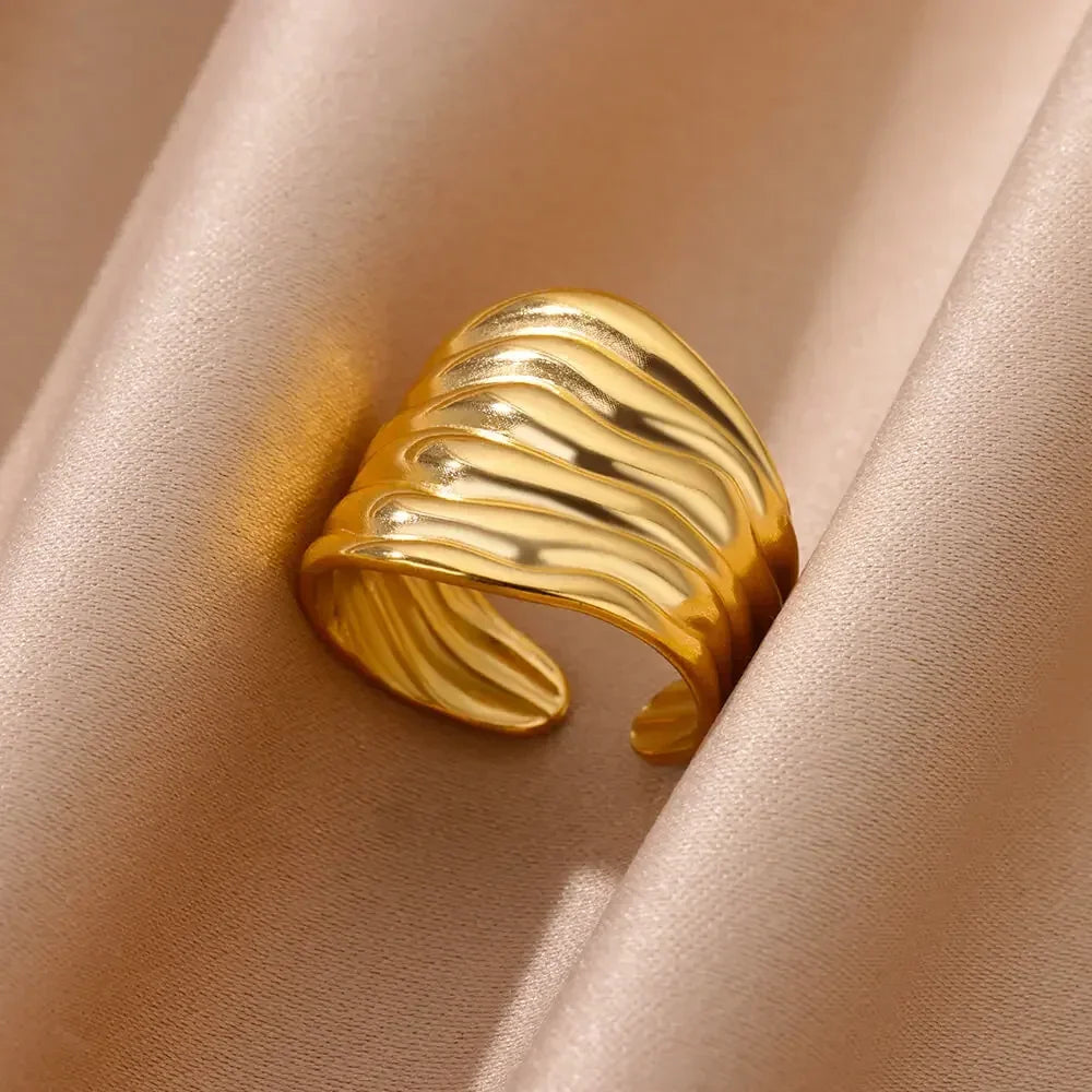Elegant gold wave design statement ring on beige satin fabric