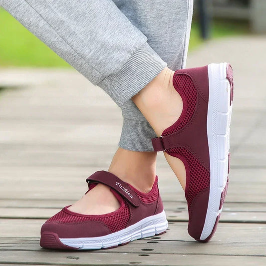 Women's burgundy mesh walking shoes with white soles and hook-and-loop strap, outdoor setting