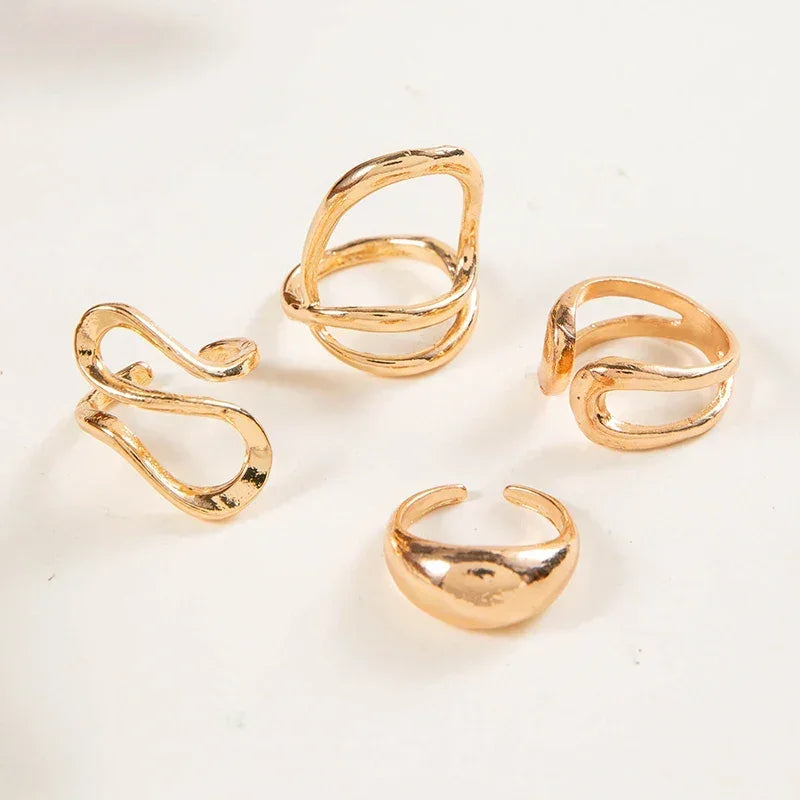 Set of four gold-tone minimalist open rings with modern abstract designs on a white background
