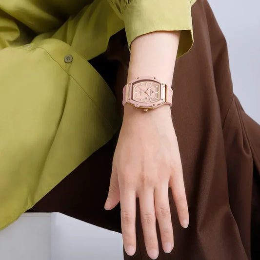 Woman wearing a stylish pink geometric wristwatch with gold accents, fashion accessory