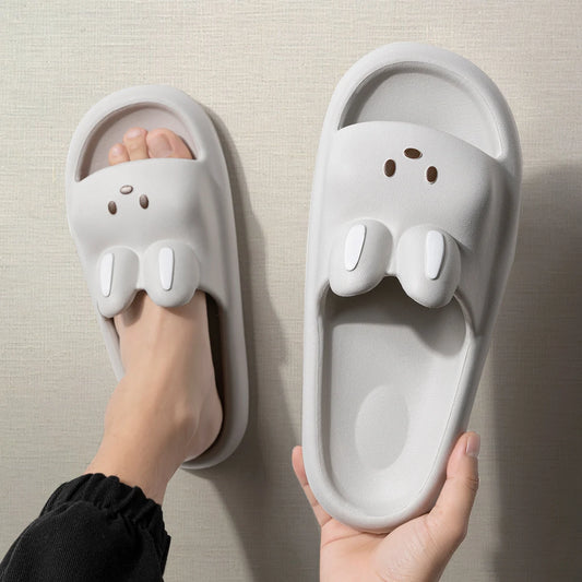Cute animal face white slip-on slippers with 3D ear design, one worn on foot, indoor setting