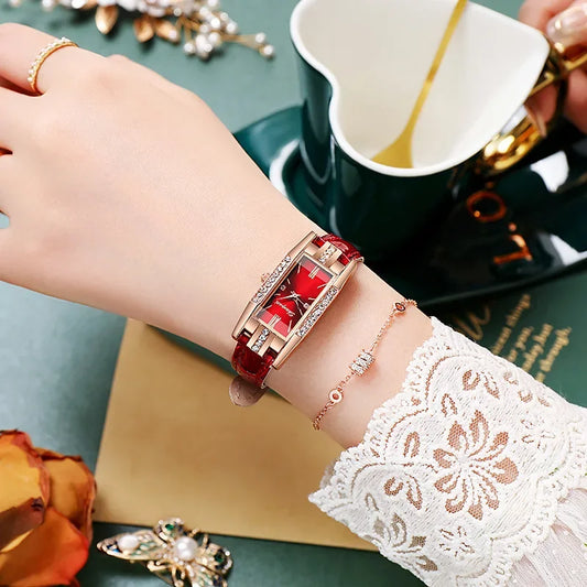 Elegant woman's hand wearing red fashion watch and bracelet, lace sleeve beside green teacup
