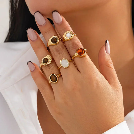 Woman's hand with manicured nails wearing multiple gold gemstone rings