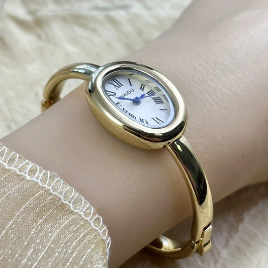 Elegant gold oval bracelet watch with roman numerals on a woman's wrist