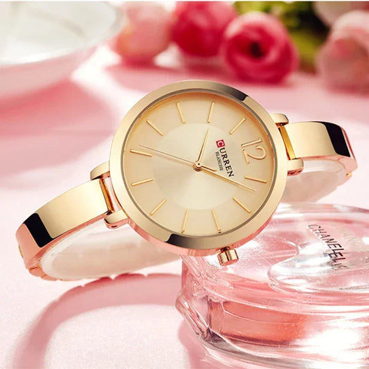 Elegant gold women's wristwatch with minimalist dial on pink background, luxury fashion accessory