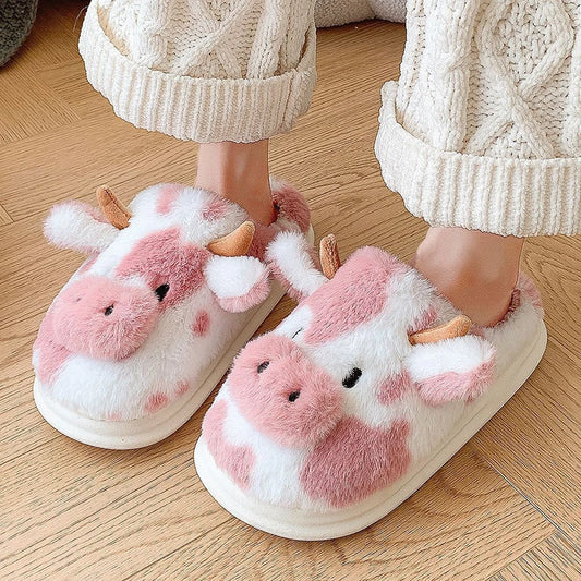 Cute pink and white cow plush slippers with horns, worn with cozy knit pants on wood floor