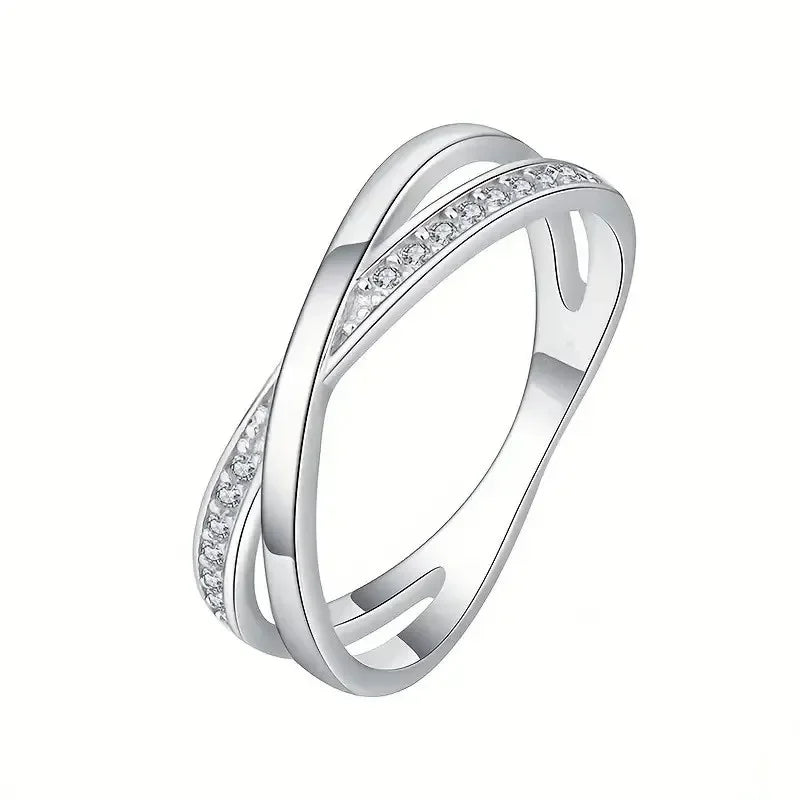 Elegant silver crossover ring with cubic zirconia accents on white background