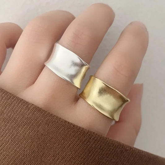 Hand wearing wide silver and gold statement rings with modern minimalist design