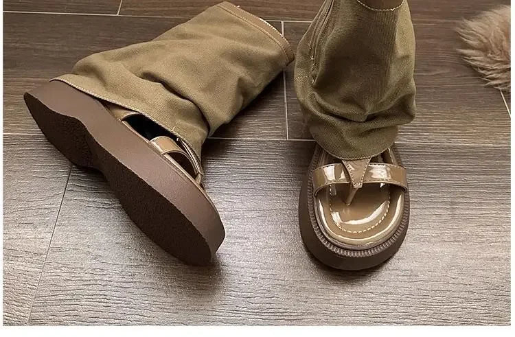 Trendy brown platform sandals with glossy finish, styled with khaki pants on wooden floor