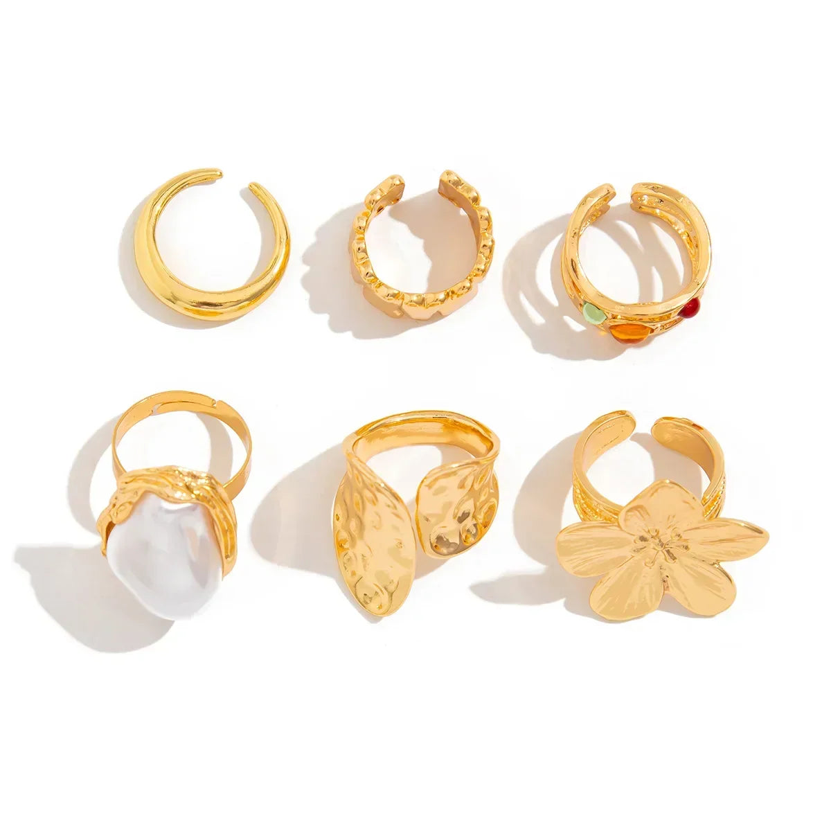 Set of six gold statement rings with assorted textured, leaf, pearl, and floral designs