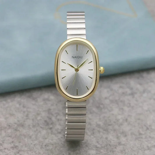 Elegant women's oval silver and gold wristwatch with minimalist design on a gray surface