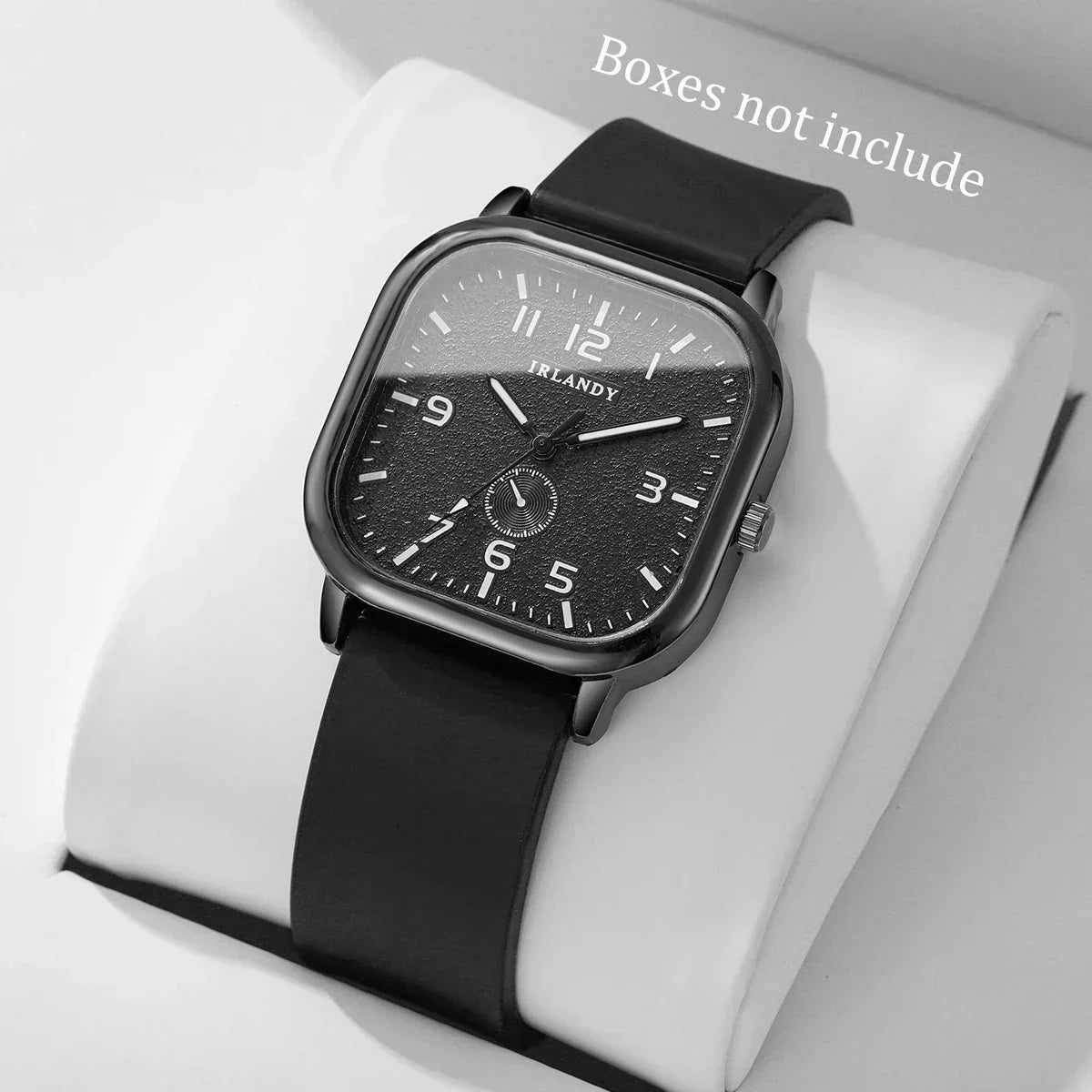 Square black wristwatch with minimalist numerals and black band on a white pillow.