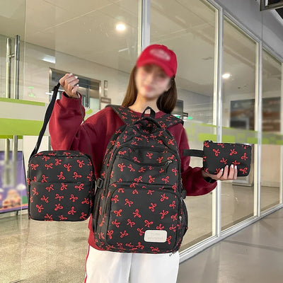 Woman holding matching black backpack, shoulder bag, and pouch with red bow pattern