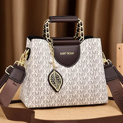 Chic brown and beige designer handbag with chain handles and gold leaf charm