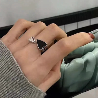 Silver adjustable heart ring with black and white enamel worn on a woman's hand