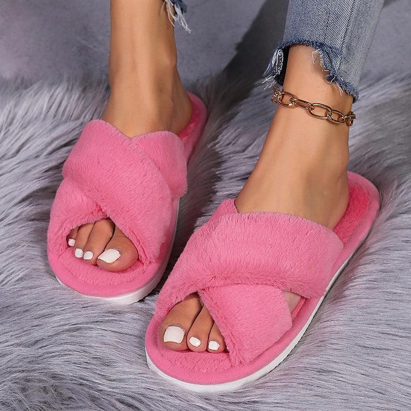 Woman wearing pink fuzzy cross-band slippers and anklet, cozy on soft grey rug