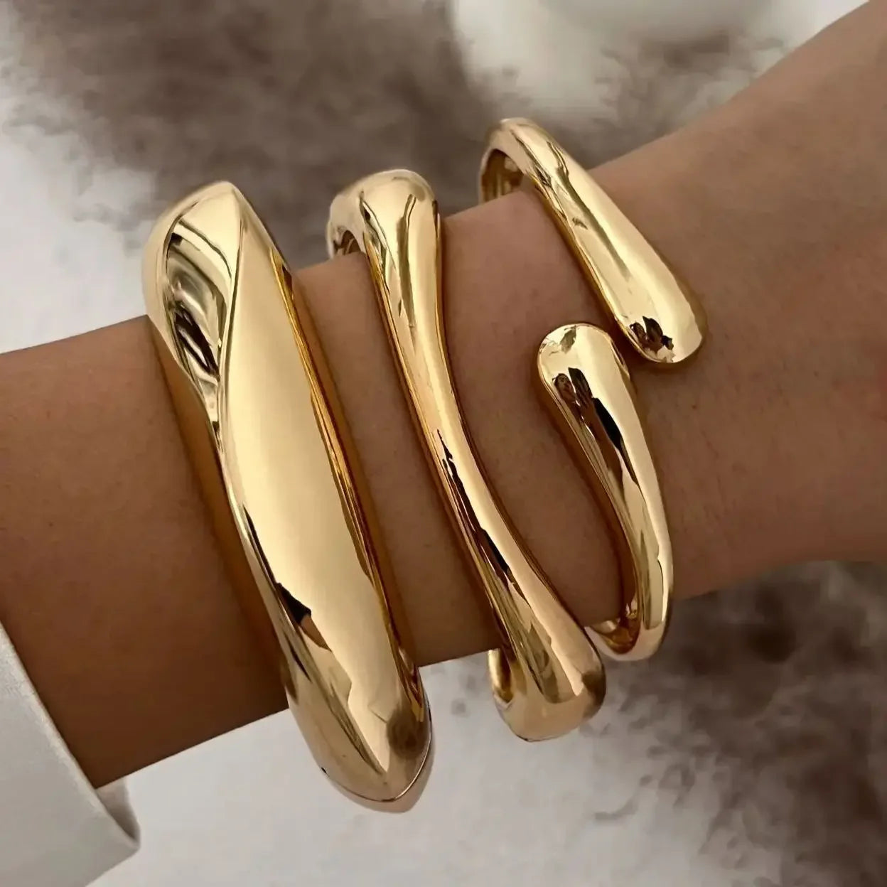 Bold gold cuff bracelet with modern sculptural design on woman's wrist