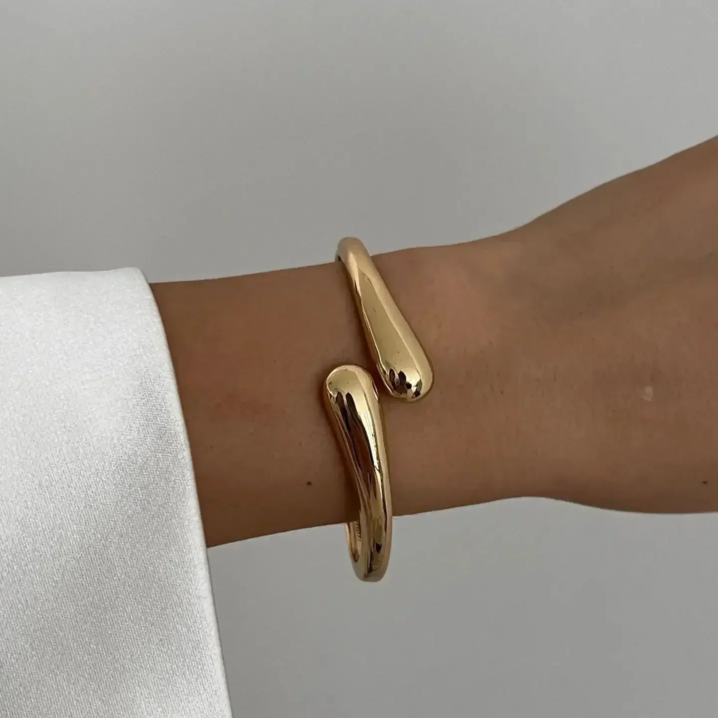 Minimalist gold open bangle bracelet on wrist, modern jewelry fashion accessory