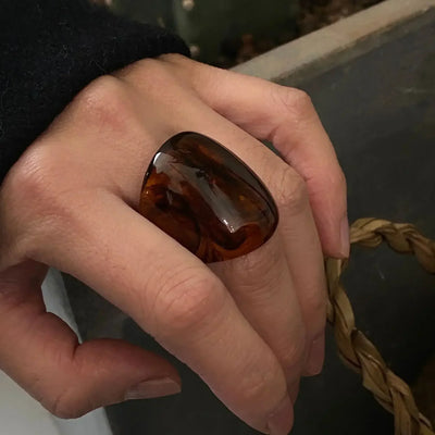 Hand wearing chunky brown resin statement ring, fashion jewelry accessory
