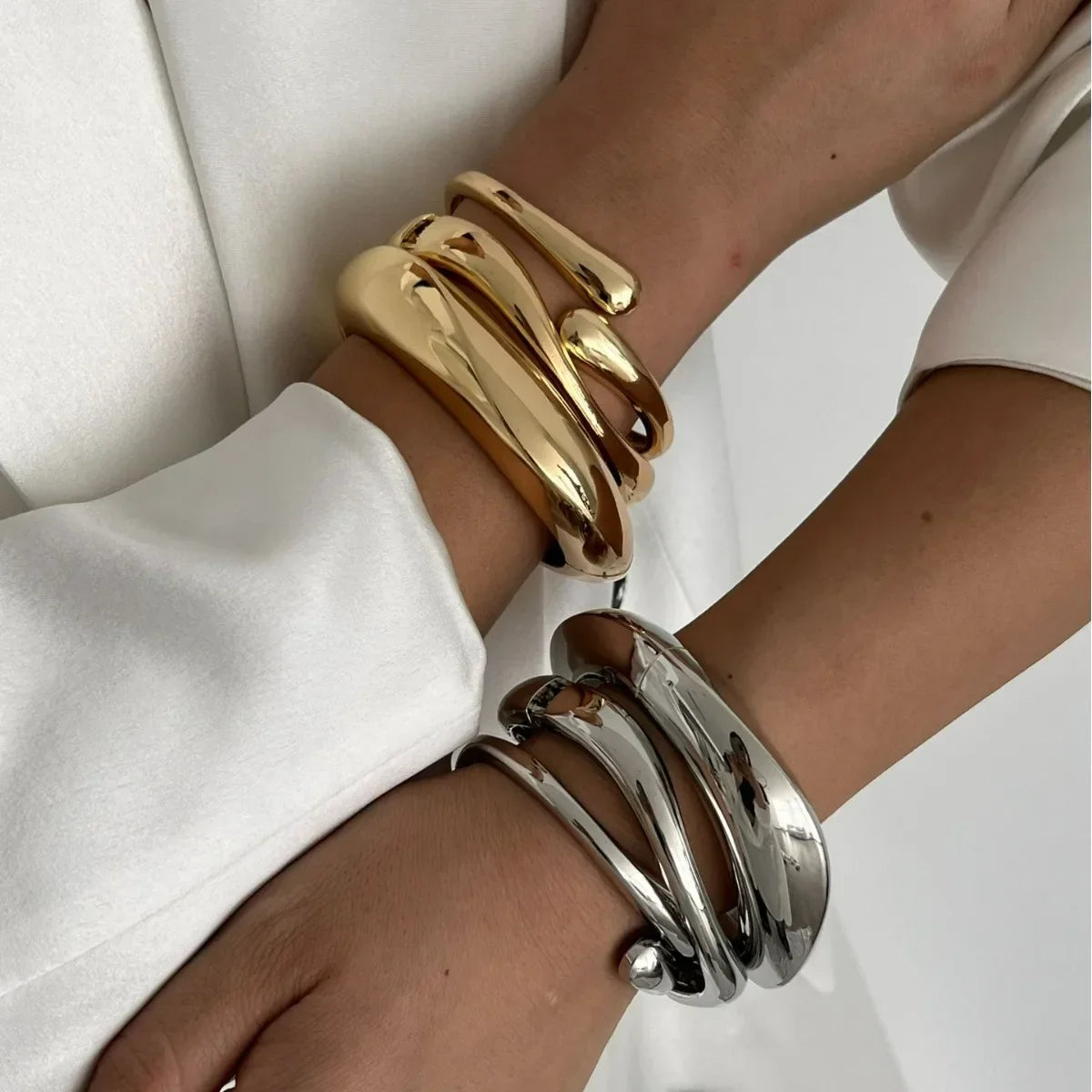 Woman wearing chunky gold and silver twisted statement cuff bracelets