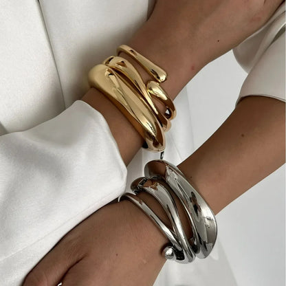 Woman wearing chunky gold and silver twisted statement cuff bracelets