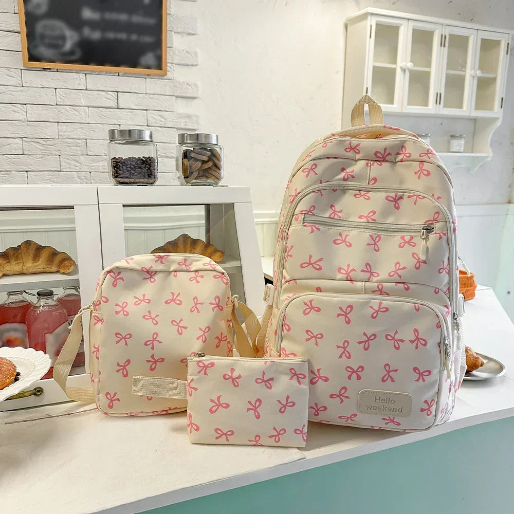 Cream backpack, crossbody bag, and pouch with pink bow print on a cafe counter