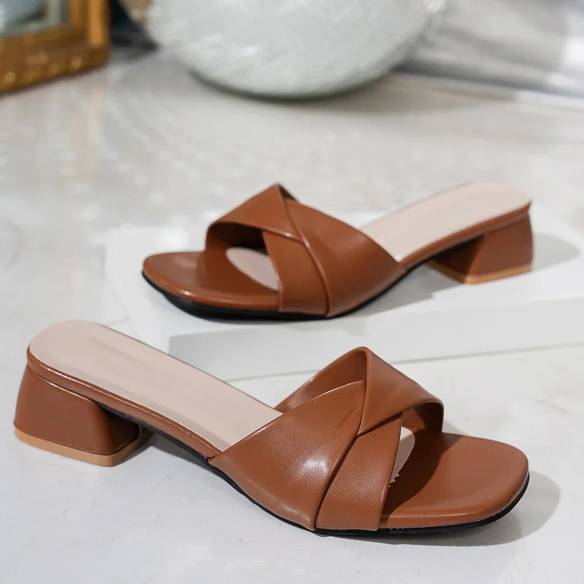 Brown block heel sandals with crisscross straps on white surface, danastors fashion shoe