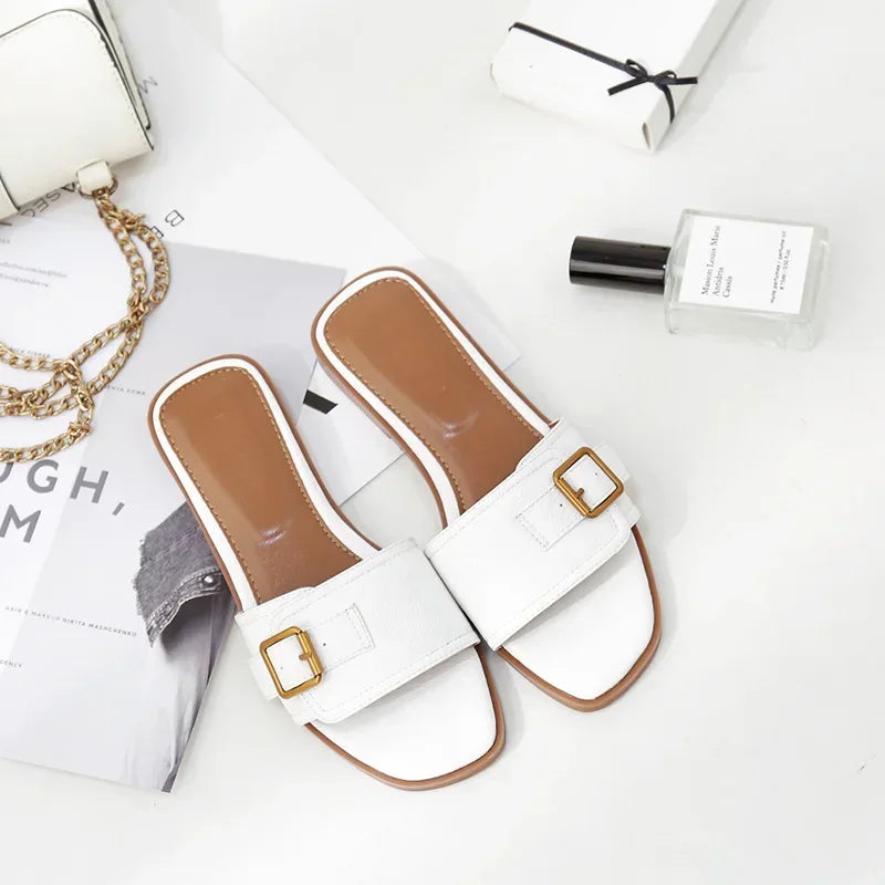 Stylish white slide sandals with gold buckles, flat heels, and square toes on a modern background
